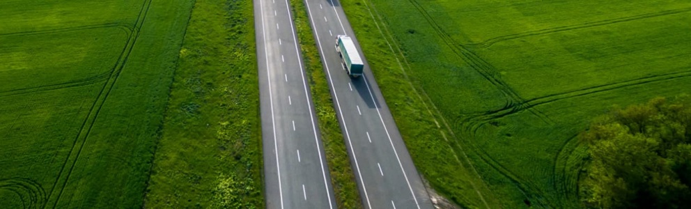 bird’s eye view of freight truck using renewable diesel to drive across green farm land