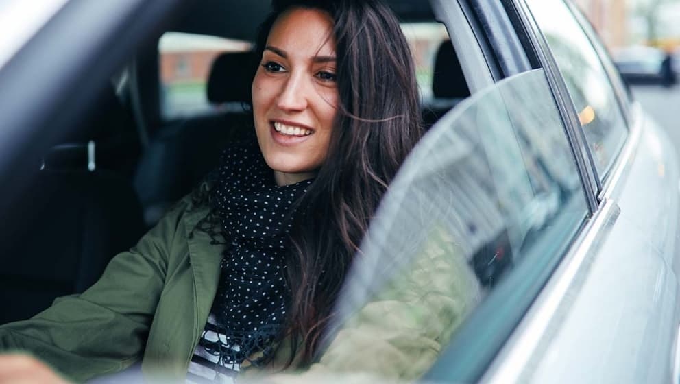 women driving passenger car smiling