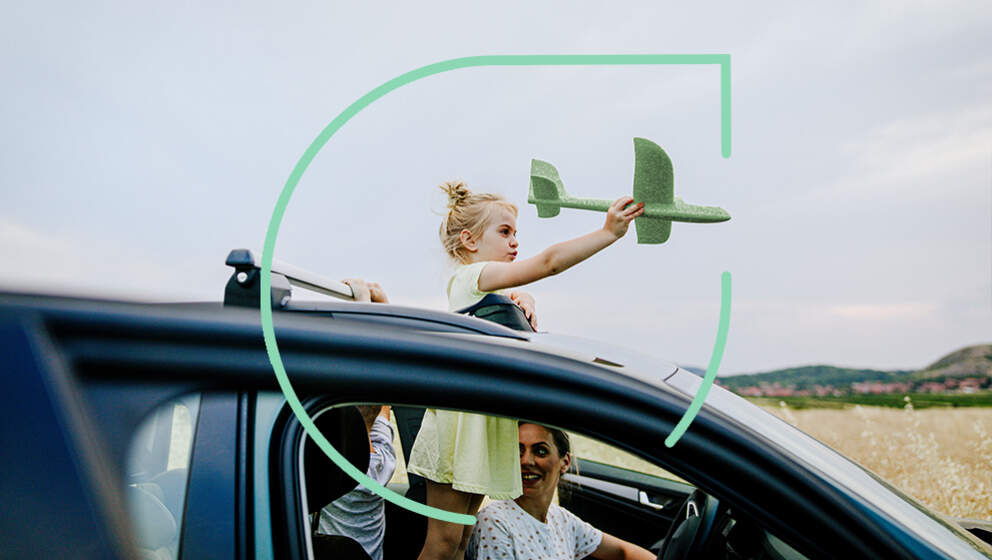 Girl in a parked car playing with toy green airplane out of the window
